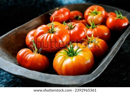 Bright red, shiney heirloom tomatoes in wooden bowl