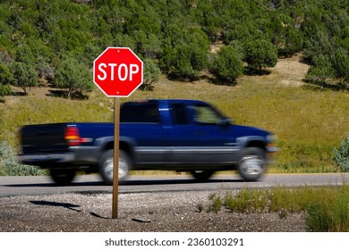 Bright red stop sign on road with blurry blurred moving car or truck speeding past 