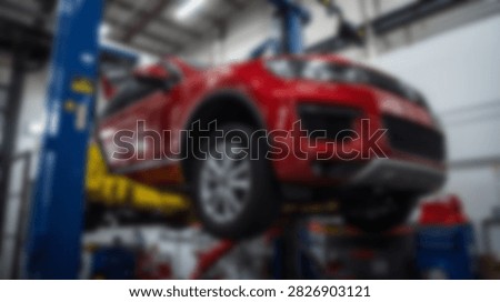 A bright red SUV is elevated on a hydraulic lift for maintenance and repair in a well-lit automotive service center.