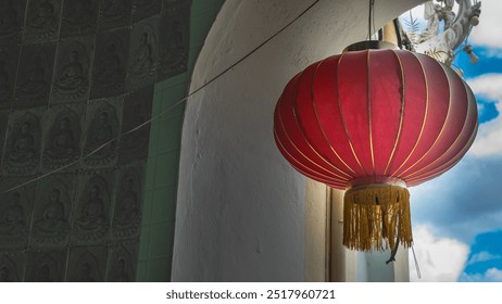 A bright red traditional Chinese lantern is suspended in the window opening of the temple. Golden stripes and fringes. Close-up. Malaysia. Penang. Kek Lok Si Temple  - Powered by Shutterstock