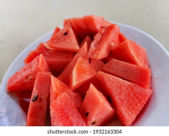 The bright red watermelon is cut on a white plate.