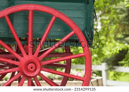 bright red wheel on vintage green farm wagon