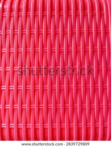 Bright red wickerwork pattern texture. Top view of woven plastic basket surface with vertical geometric rows.