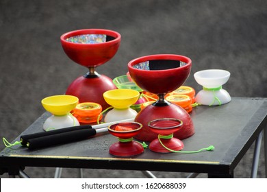 Bright red and yellow diabolos used by street performers. The diabolo is commonly misspelled as diablo. It  is a juggling prop consisting of an axle and two cups. This object is spun using a string.