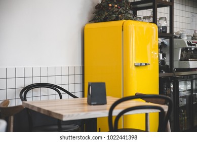bright retro yellow fridge in coffeehouse with empty tables