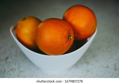 Bright Ripe Navel Oranges In A White Bowl On A Kitchen Countertop