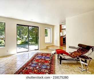 Bright Room With Resting Area And Exit To Backyard Patio. Colorful Rug On The Tile Floor And Resting Chair With Small Table