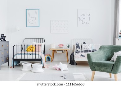 Bright Scandinavian Style Bedroom Interior With Two Metal Frame Kid's Beds, One White, One Black, And Green Armchair For Caretaker. Posters Of A Rabbit And An Elephant On White Wall. Real Photo