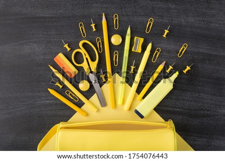 Bright school stationery falling from pencil box concept. Top above overhead view photo of set falling arranged yellow stationery and pencilbox isolated on blackboard
