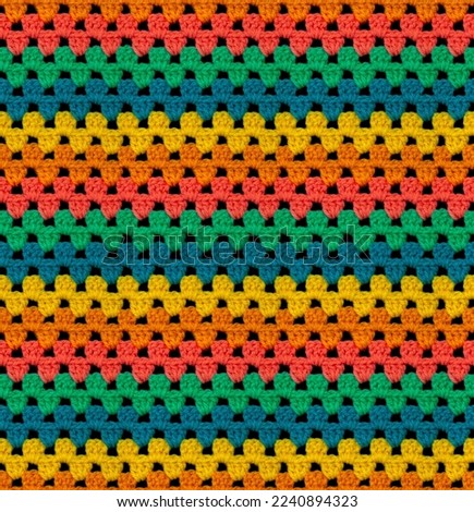 Bright seamless knitted texture. The pattern is crocheted from multi-colored acrylic yarn. Zigzag shapes. African motives. 