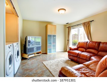 Bright Small Living Room With Brown Leather Couch, Tv And Cabinet. Room Has A Built-in Laundry Area With Washer And Dryer