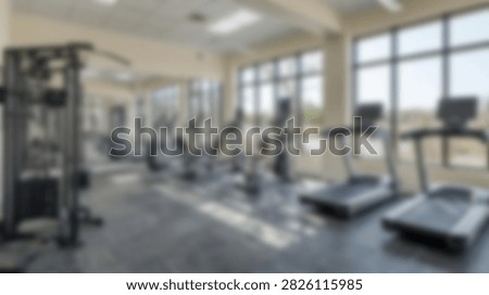 Bright and spacious gym interior featuring cardio equipment like treadmills and strength training machines, with large windows.