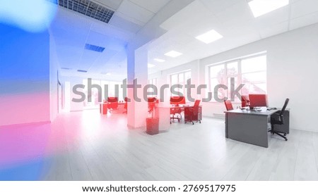 A bright and spacious office interior featuring workstations, computers, and chairs, bathed in natural light from large windows.