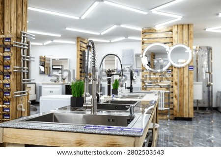 Bright and spacious showroom interior featuring modern stainless steel kitchen sinks with stylish pull-out faucets on speckled granite countertops with natural wooden bases