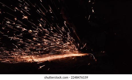 bright sparks from a circular in the dark on a black background close-up. A worker cuts metal with a circular saw close-up. Working with iron. - Powered by Shutterstock