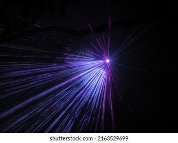 A bright spotlight projects lilac blue rays in a dark night space. Laser show. Blurred image