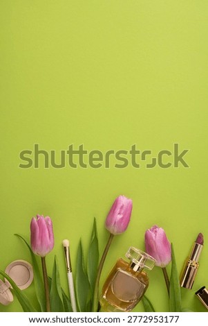 Bright spring flatlay featuring pink tulips, glass perfume bottle and makeup items on a fresh green background conveying beauty, gift, femininity and elegant lifestyle