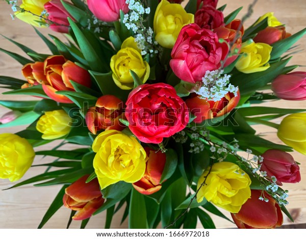 Bright spring flowers tulips bouquet on the table\
directly above view, colorful pink, red and yellow blooming tulips\
in vibrant colors