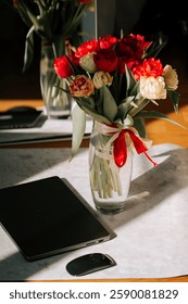 Bright spring work setting featuring a laptop and a vase of colorful tulips in warm sunlight