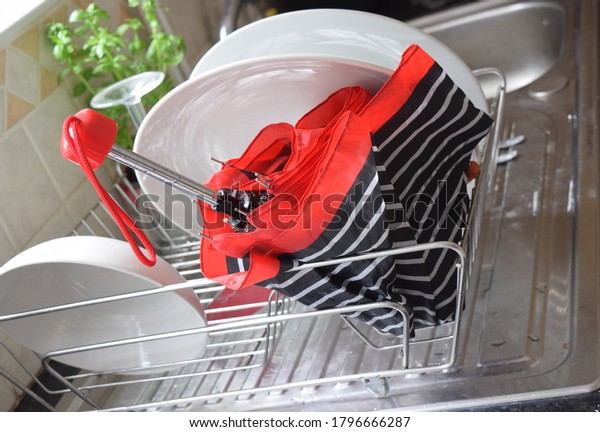 Bright striped umbrella is drying in the dish\
rack in kitchen\
interior.