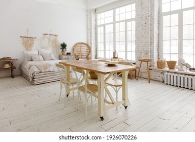 Bright Studio Interior With Rustic Wooden Bed, Table, White Wooden Floor And Large Windows