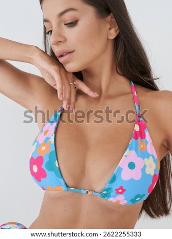In a bright studio, a model gracefully poses in colorful floral swimwear.