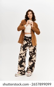 Bright studio setting features young woman in trendy outfit with eye-catching cow print pants