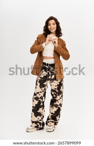 Bright studio setting features young woman in trendy outfit with eye-catching cow print pants