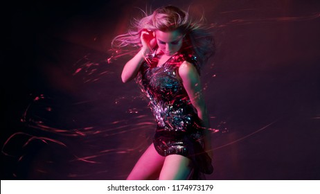 Bright and stylish young woman dancing in club, color light, motion effects. Black background, long exposure