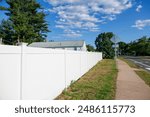 Bright suburban neighborhood with white fences and clear blue sky.