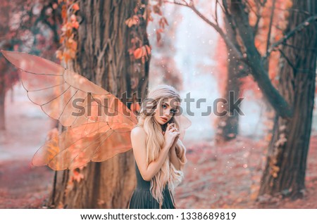 bright summer photo with shining rays of sun, mysterious forest fairy fell in love with prince, girl with puppet face, blond long hair and blue eyes, lady in green dress peeps modestly, with interest.
