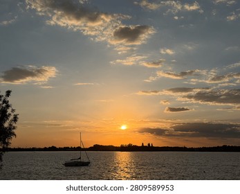 Bright Sun Breaking Through Clouds in Dramatic Sunset Over the Lake