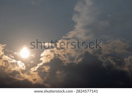 Bright sun breaking through dark dramatic storm clouds in the sky during late afternoon.