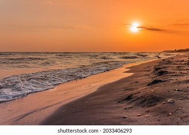 Bright sun on horizon over coastline of sandy beach during sunset