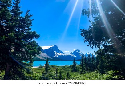 Bright sun rays fall on a forest lake in the mountains. Sunshine over mountain lake. Mountain lake sunshine landscape. Mountain lake view in sunny day with sunshine