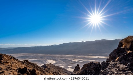 Bright sun setting over the Badwater Basin and the Black Mountains viewed from Dantes View in Death Valley, California, USA