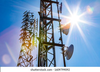 Bright sun shine over two cell site towers, radio and GPS transmitter and receiver, associated with electromagnetic pollution, with vibrant lens flare
