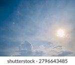 Bright sun shining through dramatic clouds above Jakarta, Indonesia. Upward view with soft lens flare, blue sky and natural light, creating a hopeful mood, ideal for weather, energy and nature themes.