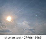 Bright sun shining through dramatic clouds above Jakarta, Indonesia. Upward view with soft lens flare, blue sky and natural light, creating a hopeful mood, ideal for weather, energy and nature themes.