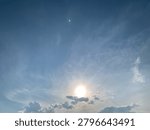 Bright sun shining through dramatic clouds above Jakarta, Indonesia. Upward view with soft lens flare, blue sky and natural light, creating a hopeful mood, ideal for weather, energy and nature themes.