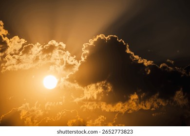 Bright sun shining through dramatic golden clouds with sun rays piercing the sky during a moody sunset or sunrise. High quality photo