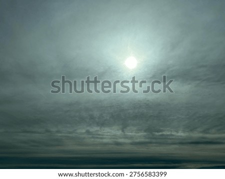 Bright sun shining through dramatic cloudy sky with atmospheric haze and moody light conditions