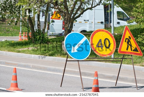 Bright sun, spring, summer. Road signs with work\
truck on construction\
road.