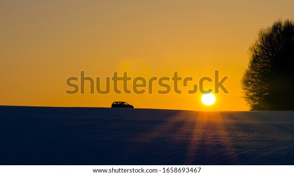 Bright sun at sunset. Car on the\
horizon in the sun. The outlines of the trees in the\
sunlight.