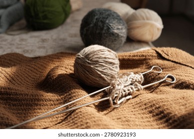 Bright sunlight pours over a work-in-progress knitting piece, showcasing soft yarn balls and gleaming knitting needles on a textured fabric, inviting creativity.