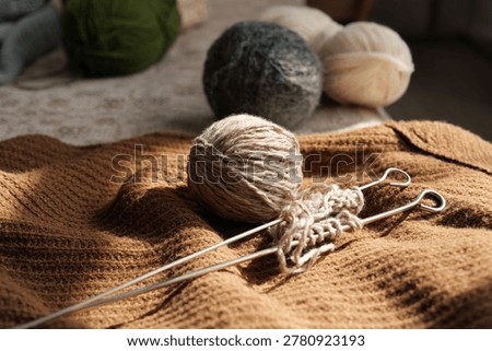 Bright sunlight pours over a work-in-progress knitting piece, showcasing soft yarn balls and gleaming knitting needles on a textured fabric, inviting creativity.
