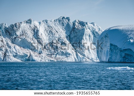 Bright sunny day in Antarctica. Full calm and reflection of icebergs in deep clear water. Travel by the ship among ices. Snow and ices of the Antarctic islands.