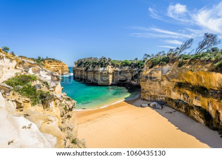 Bright sunny summer coast view to a beautiful sandy beach bay and rocky erosion sand limestone cliff of Great Ocean Road, walking at Loch Ard Gorge, Port Campbell National Park, Victoria/ Australia