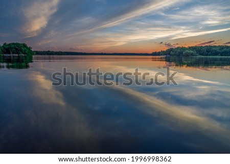Bright sunset with reflections of clouds on the calm water during summer on Big Moon Lake, Barron County WI
