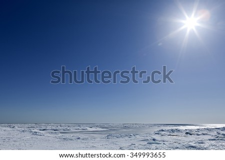 Bright sunshine above the frozen sea. Rough ice on the sea, some drifted ice and snow. April on the Baltic Sea.